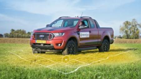 Panoramic image showing a red Ford Ranger pickup truck parked in a field or agricultural area. The image has white geometric line overlays, suggesting it's being used for some kind of mapping, surveying, or precision agriculture application. The background shows green vegetation and a blue sky.