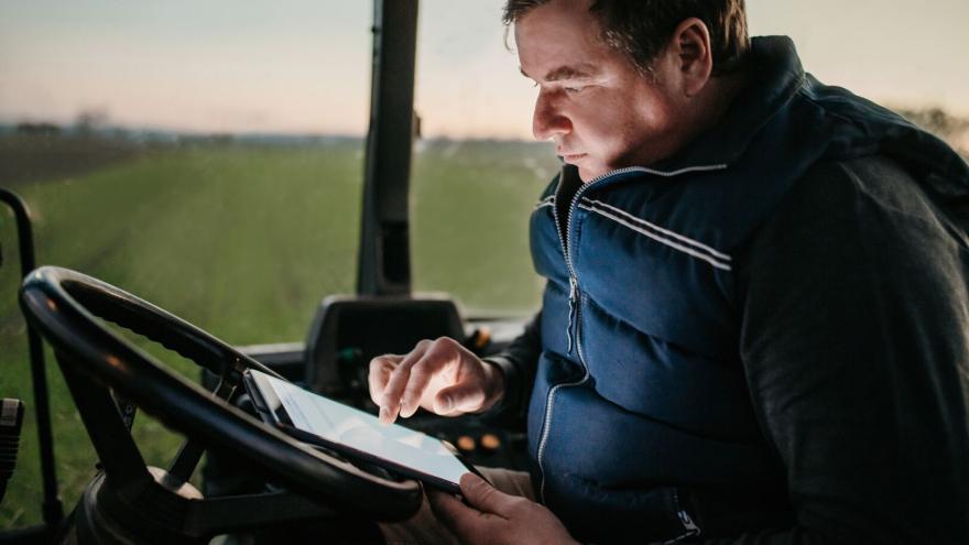 Agricultor en tractor con un ipad revisando los tratamientos